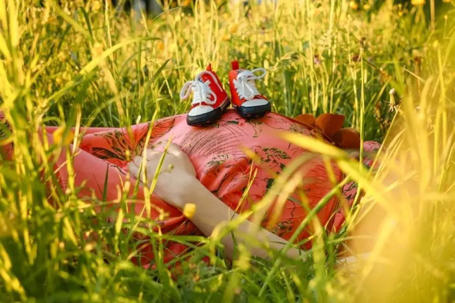 pregnant woman with baby shoes on belly, stressed out waiting for her baby to arrive